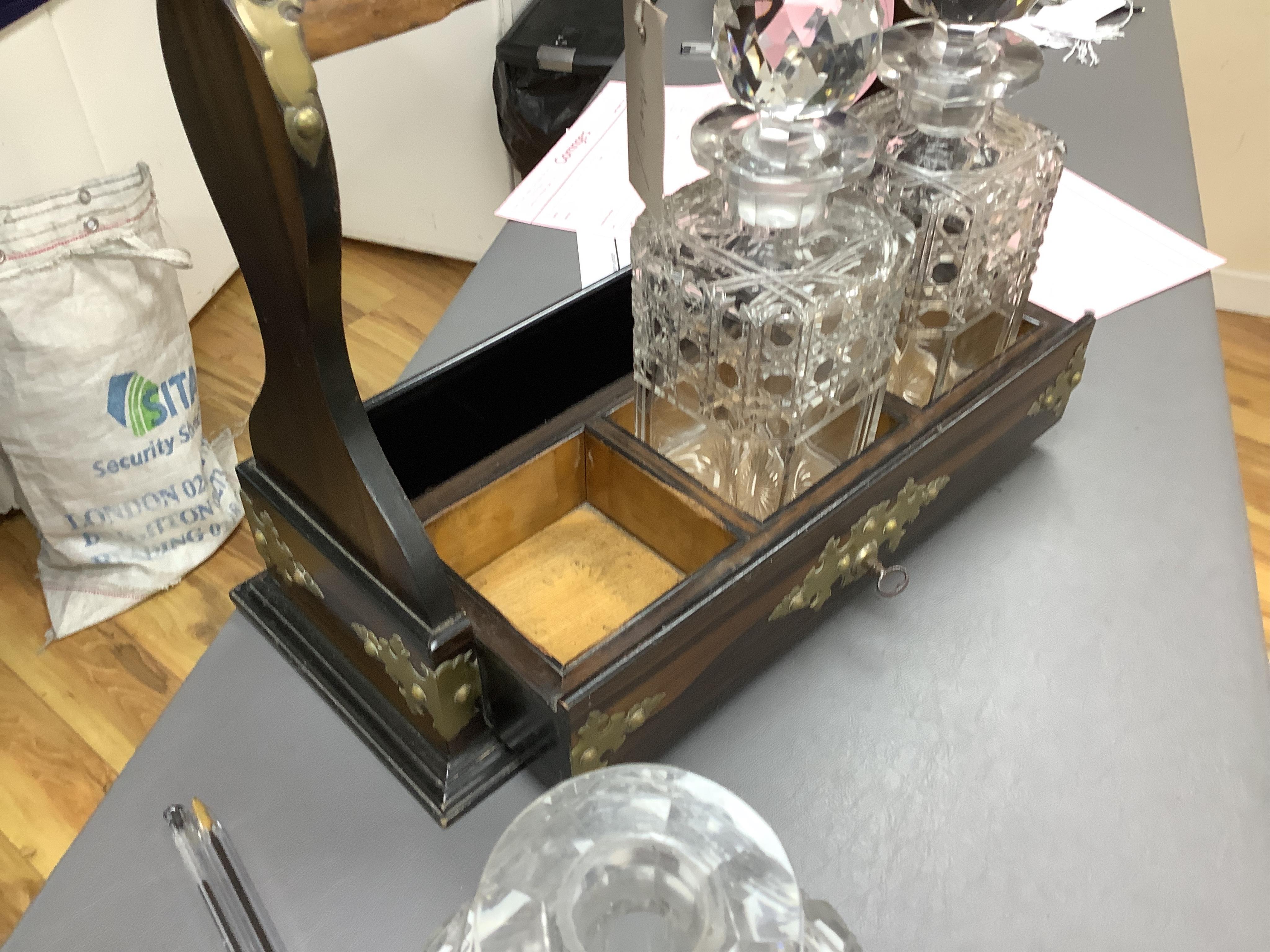 A Victorian coromandel three-bottle tantalus with brass mounts and original key